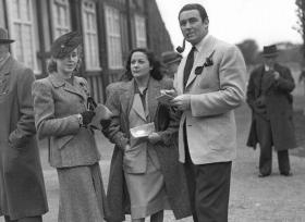 The ‘Gorgeous Gael’, Jack Doyle, with his wife Movita (centre) and friend at the Phoenix Park races c. 1945—‘He wears an orange tie knotted in the Duke-of-Windsor manner and a suit which is so draped in shape that it is far more characteristic of Lenox Avenue, New York, than O’Connell Street, Dublin.’ (RTÉ Stills Library)