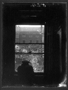 The same building through the shattered window pane of house on the far (west) side of the street.