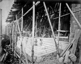 The north side of the nave during reconstruction. Street rebuilt the failing arcade piers while retaining the upper elevation in place, seen here propped up on massive baulks of timber. (National Library of Ireland)