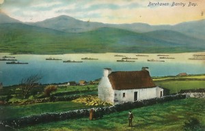 There is much about this picture that is typical of the Irish postcard. Even today, a century after this photograph was taken and coloured, you would not have to search long for a similar scene of a whitewashed thatched cottage with deep blue water behind it and the green hills rising in the background. The destroyer flotilla in the middle ground isn’t quite so typical these days, but in the early years of the twentieth century the might of the Royal Navy was something commonly seen in Irish waters. In the case of Berehaven, it was not just the odd destroyer force that briefly dropped anchor in Bantry Bay:  battleships, and indeed whole battle squadrons, were regular visitors, for these were home waters to the British Home Fleet, and the Atlantic was the exercise ground and playground of all the terrible great ships of which HMS Dreadnought was only the most famous. (Fergus O’Connor/Adrian Healy